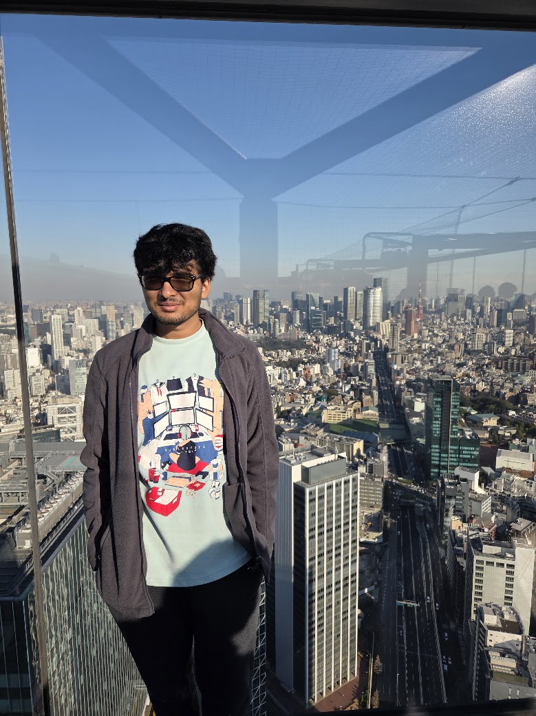 Tanish Shah standing in front of a window over the Tokyo skyline